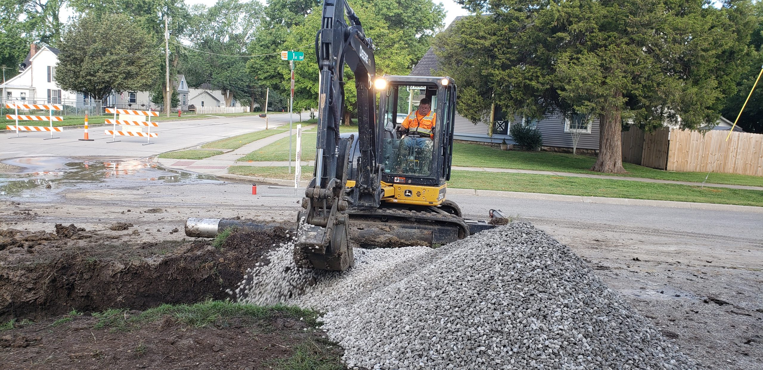 A utility worker uses a backhoe to repair a broken water line