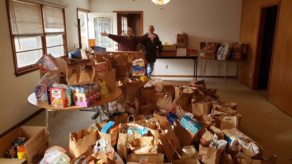 Volunteers at the Edgerton food pantry stand behind hundreds of bags of food donated by Edgerton Elementary families