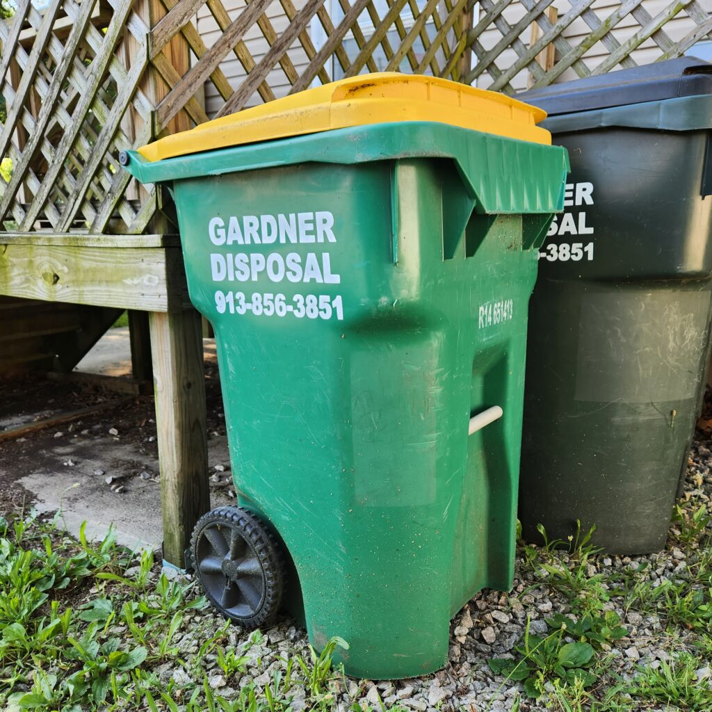 A green recycling bin outside a home in Edgerton