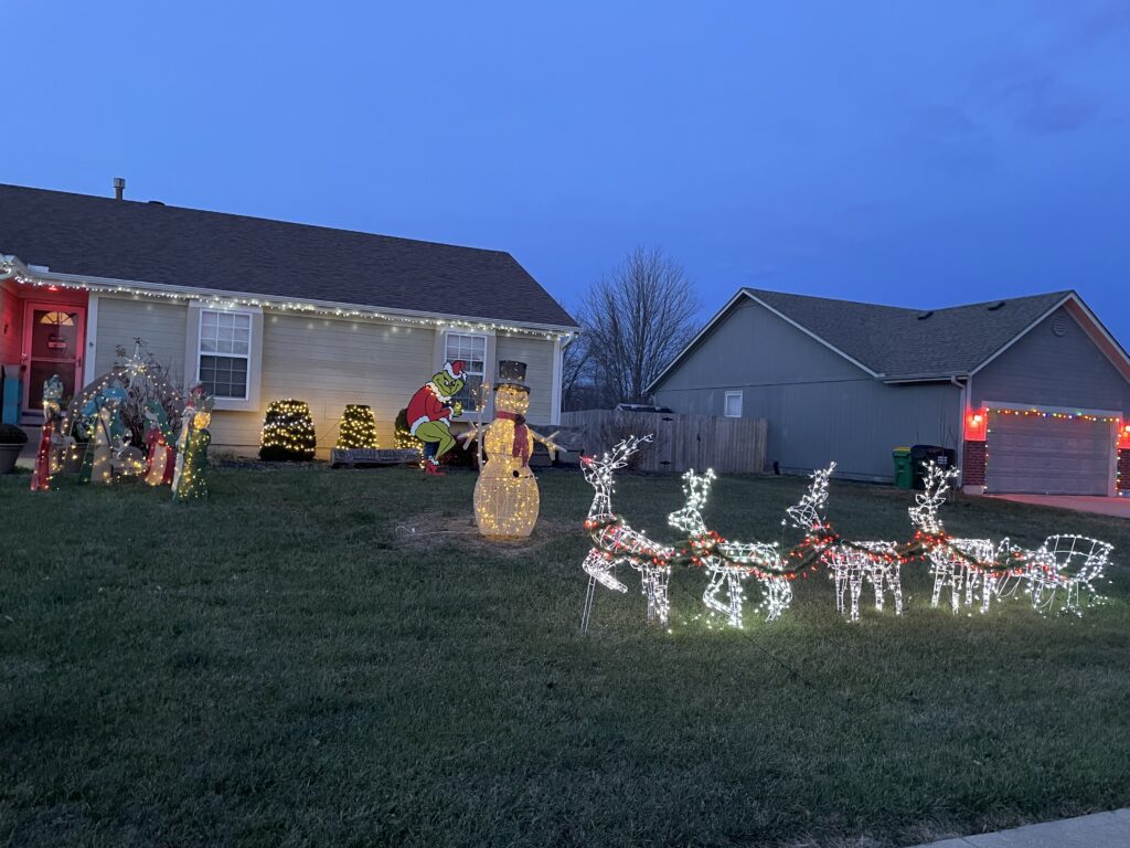 A house with Christmas lights. Reindeer pulling a sleight, a snowman and a nativity scene.
