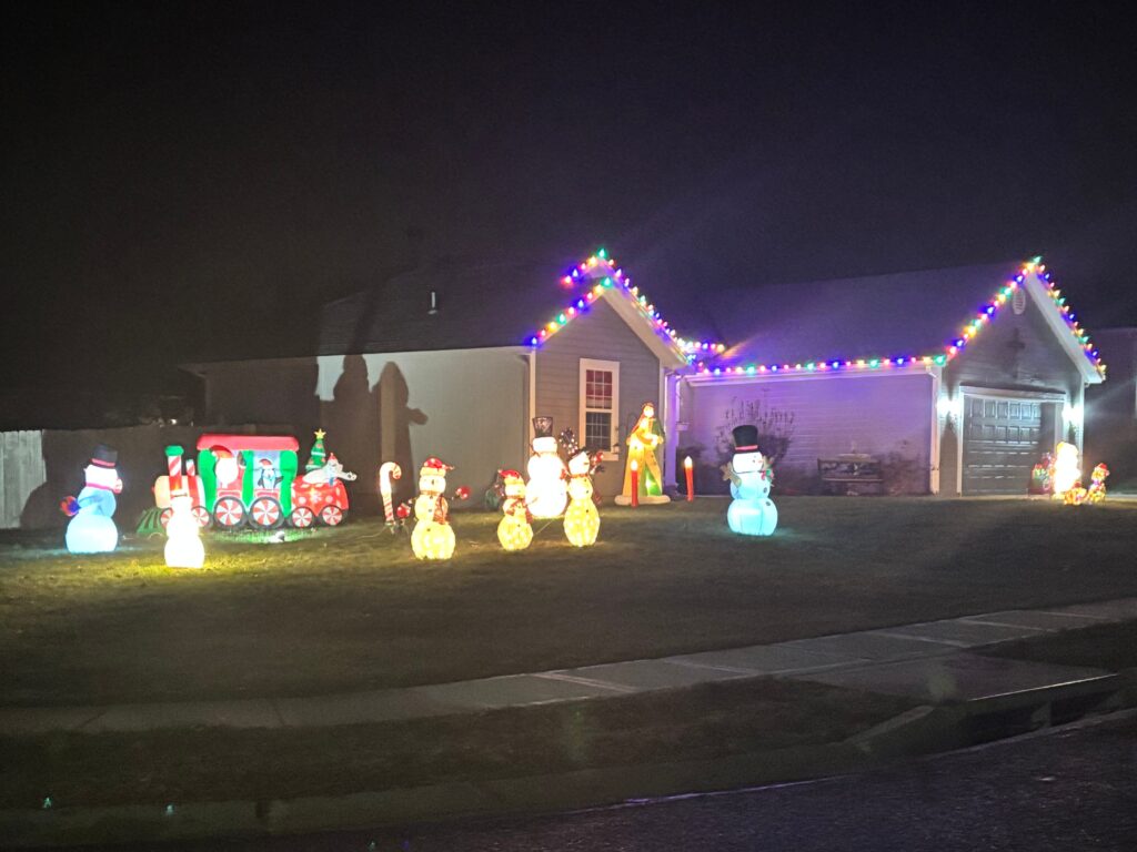 Snowmen and gnomes decorate this front yard while multicolored lights adorn the roof line.